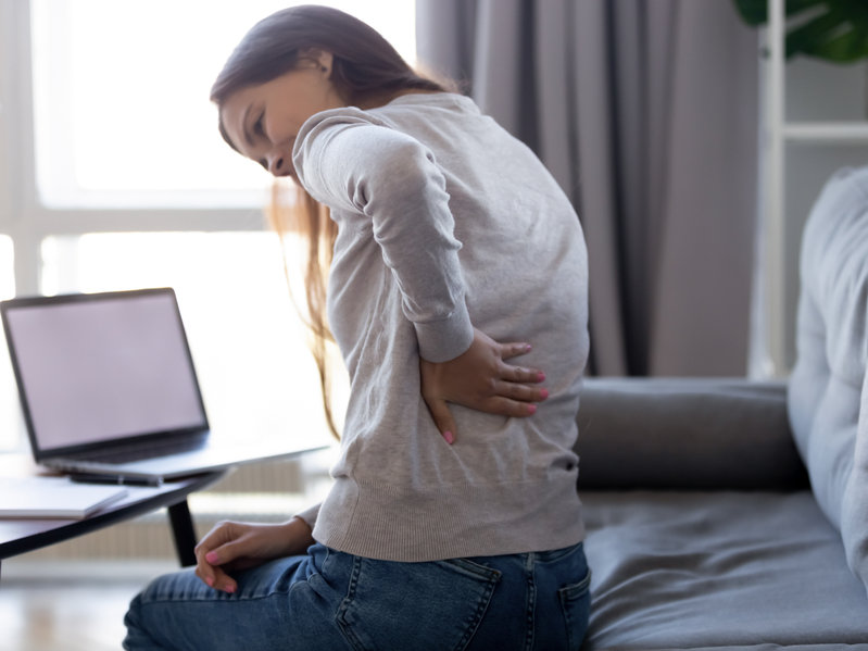 A woman holding her lower back while dealing with back pain