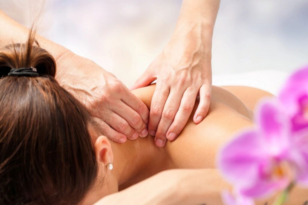 A massage therapist applying focused pressure to a client's upper back and neck